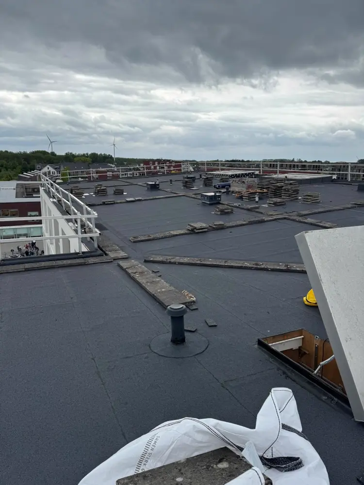 Dakdekkers bezig met reparatie van een plat dak in Arnhem