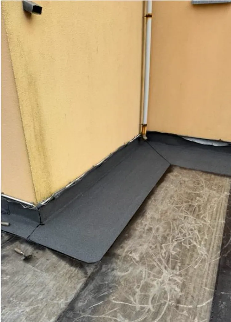 Nieuwe bitumen aansluiting tussen een plat dak en de gevel in een binnenhoek, bij een project in Barneveld