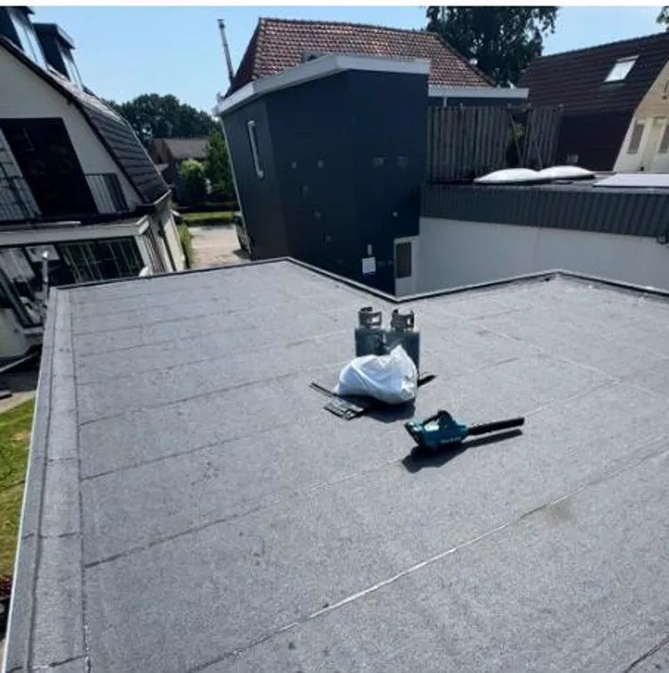 Plat dak van een woning in Westervoort met nieuw gelegd dakleer (bitumen) en het gereedschap van de dakdekker